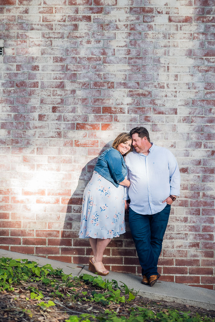 Couple leaning together beside a brick wall