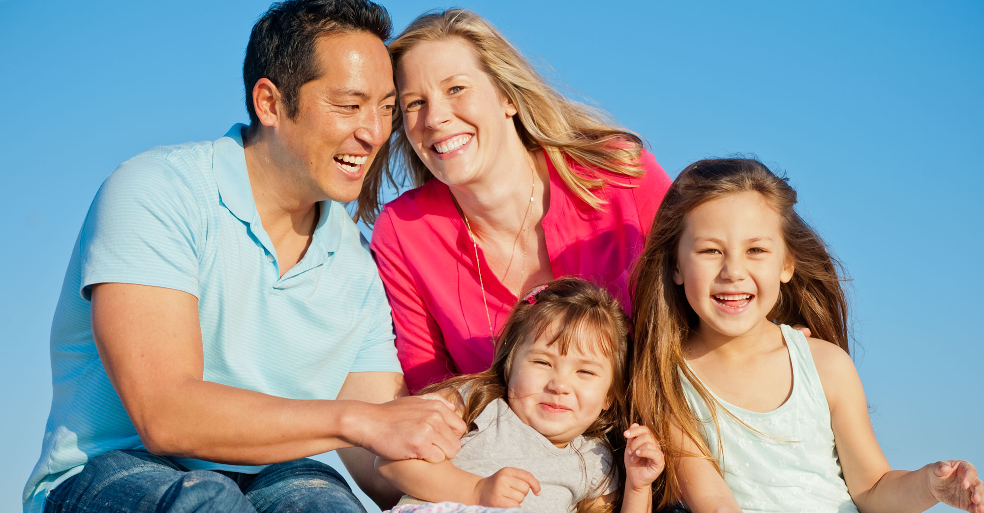Family laughing together beneath a clear blue sky