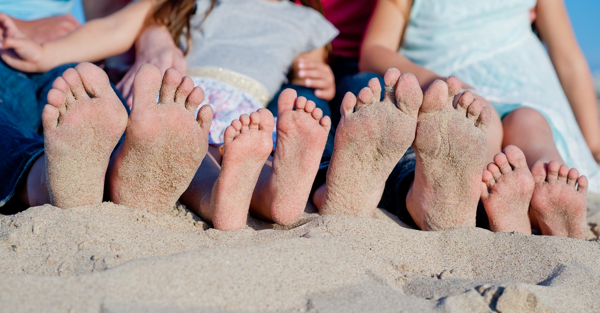 A family's sandy feet lined up on Hermosa Beach